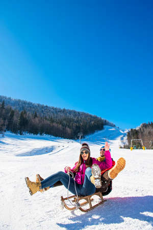 Young happy couple sledding in winter at ski centerの写真素材