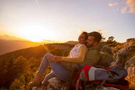 Couple Man and Woman sitting on cliff enjoying mountains and clouds landscape Love and Travel happy emotions Lifestyle concept.の写真素材