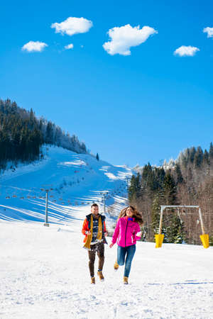 Snowball fight. Winter couple having fun playing in snow outdoors. Young joyful happy multi-racial couple.の写真素材