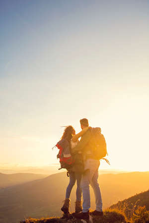 Hikers with backpacks relaxing on top of a mountain and enjoying the view of valley.の写真素材