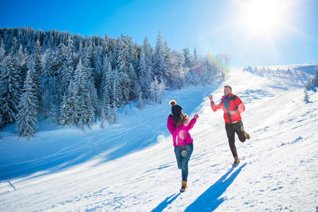 Snowball fight. Winter couple having fun playing in snow outdoors. Young joyful happy multi-racial coupleの写真素材
