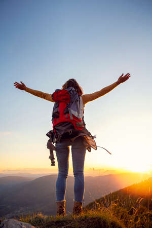 cheering woman hiker open arms at mountain peakの写真素材