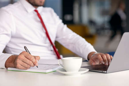 Portrait of young man sitting at his desk in the office.の写真素材