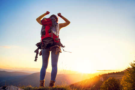 cheering woman hiker open arms at mountain peakの写真素材