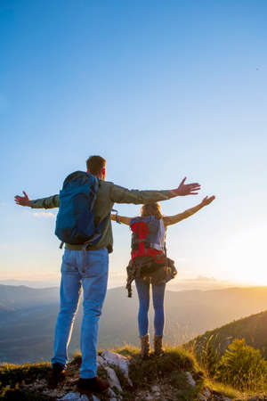 Couple with raised arms holding hands and looking at sunset.の写真素材