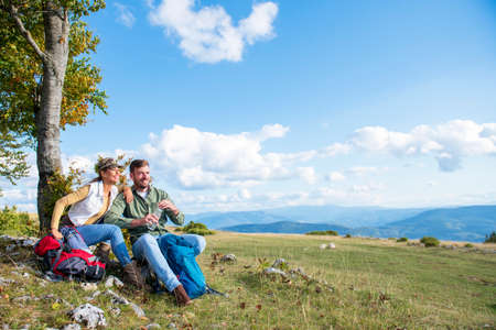 Young couple drinking water while resting on the rock during the travel in the mountainsの写真素材