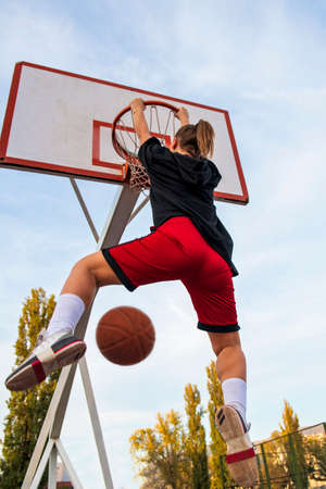 Females playing basketball on street court. Woman streetball player making slam dunk in a basketball gameの写真素材
