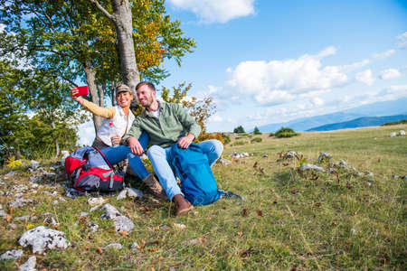 Cheerful young couple taking a selfie outdoor during the travel in the mountainsの写真素材