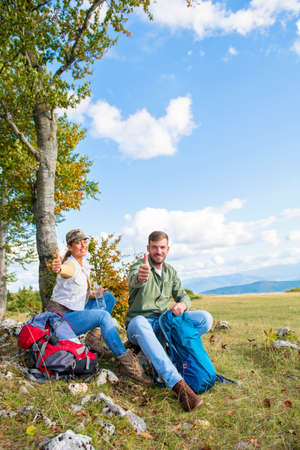 Young couple drinking water while resting on the rock during the travel in the mountainsの写真素材