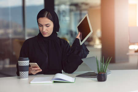 professional young muslim business woman using mobile digital tablet computer at workの写真素材