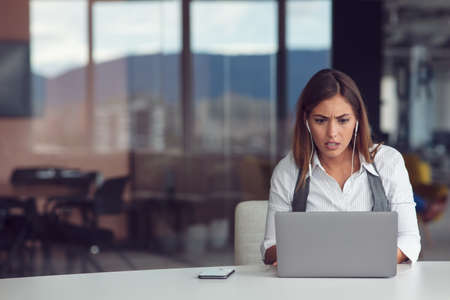 Portrait of focused woman in headphones taking part in webinar in officeの写真素材