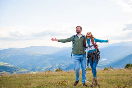 Happy travelers couple conquered top of mountain, raises hands upの写真素材