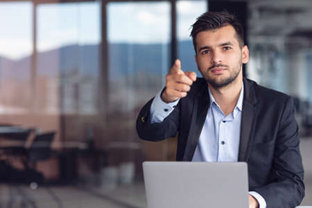 Man Sitting At Office Desk With Laptop Pointingの写真素材