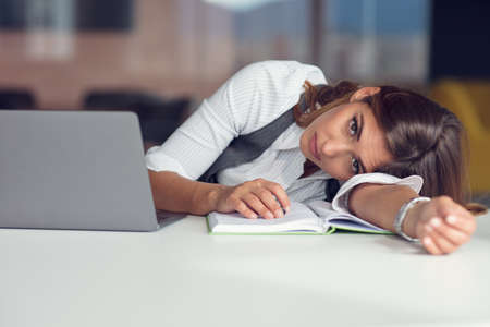 Overworked and tired young woman sleeping on desk at office. Frustrated, business.の写真素材