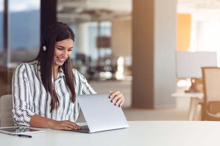 Portrait of focused woman in headphones taking part in webinar in office