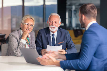 Positive aged couple consulting with insurance agentの写真素材