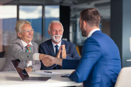 Positive aged couple consulting with insurance agentの写真素材