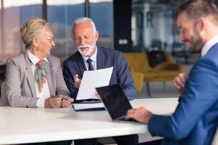 Positive aged couple consulting with insurance agentの写真素材