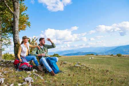 Young couple drinking water while resting on the rock during the travel in the mountainsの写真素材