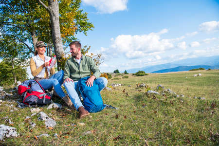 Young couple drinking water while resting on the rock during the travel in the mountainsの写真素材