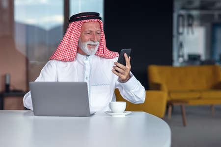Arab businessman laptop computer in modern office using phoneの写真素材