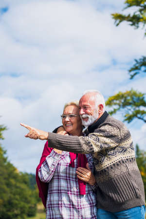 Elderly couple embracing in autumn park. Enjoying in love.の写真素材