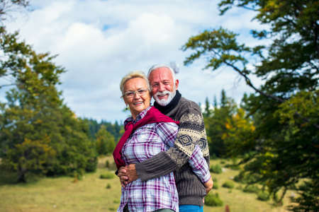 Elderly couple embracing in autumn park. Enjoying in love.