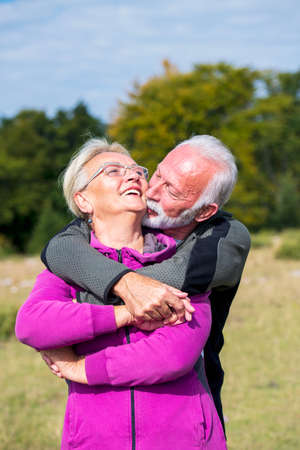 Elderly couple embracing in autumn park. Enjoying in love.の写真素材