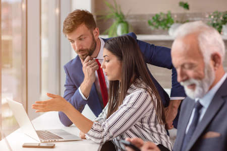 Portrait of a group of diverse corporate colleagues standing next to window at a table in a bright modern officeの写真素材
