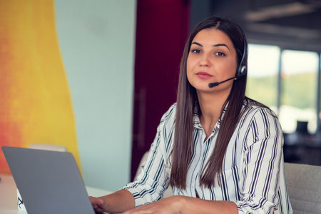 Young friendly operator woman agent with headsets working in a call centre.の写真素材