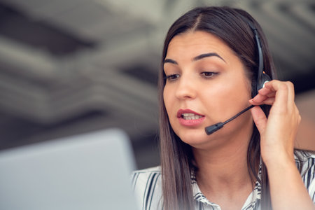 Young friendly operator woman agent with headsets working in a call centre.の写真素材
