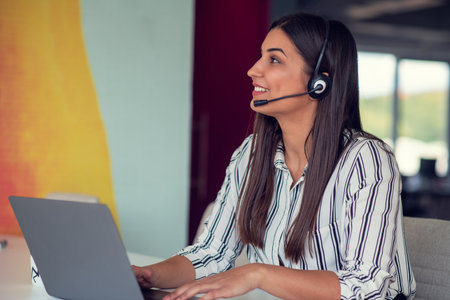 Young friendly operator woman agent with headsets working in a call centre.の写真素材