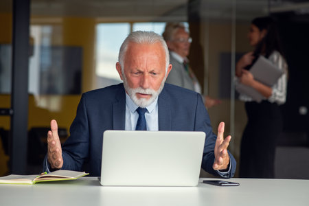 Senior businessman working on laptop computer in modern officeの写真素材