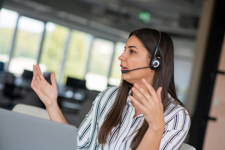 Brunette Lady Video Calling On Laptop Wearing Headphones Smiling And Waving Hand To Webcam Communicating Onlineの写真素材