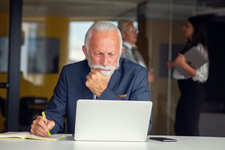 Senior businessman working on laptop computer in modern officeの写真素材