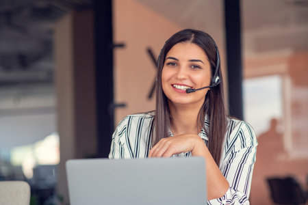 Young friendly operator woman agent with headsets working in a call centre.の写真素材