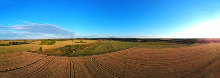 Panorama of divided fields of grain, meadow and tees, village, aerial view.