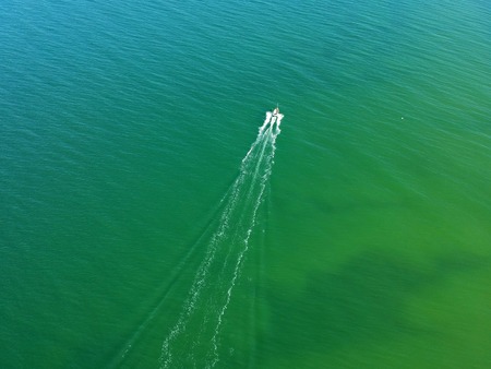 Aerial view on small fishing boat sailing straight at sea waters