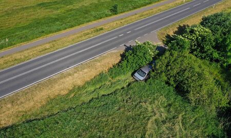 Aerial drone perspective view on car accident hitting the bushes and roadside, high speed on curve...