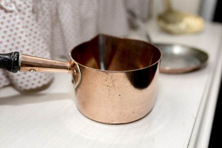 Victorian copper saucepan in a Victorian kitchen setting on a white wood chest of drawers in the UKの写真素材