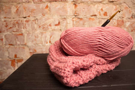 pink yarn and warm crochet yarn hat for crocheting on a dark table.
