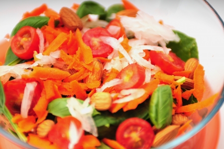 A healthy vegan salad with tomatoes, lettuce, spinach almonds and carrotsの写真素材