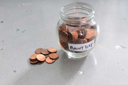 A jar of pennies for a rainy day on a decorative concrete backgroundの写真素材