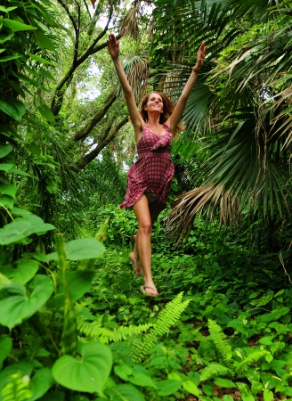Beautiful young woman jumping for joy in forestの写真素材