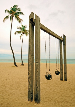 Swings at a park near the ocean on a warm tropical beachの写真素材