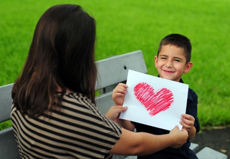 young boy giving his mother a heart drawing for a presentの写真素材