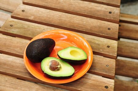 Sliced avocado on orange plate with picnic tableの写真素材