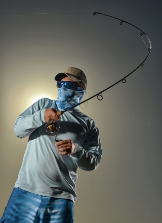 Man fishing in blue shorts, a hat and sunglassesの写真素材