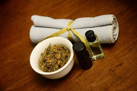 two bottles of essential oil with herbs and wash cloth for beauty treatment at spaの写真素材