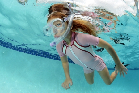 pretty girl swimming underwater in pool in summerの写真素材